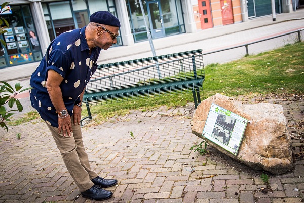 Man reads the story of the Liberation Route audio spot Weert on the plaque on the Meuse Boulder