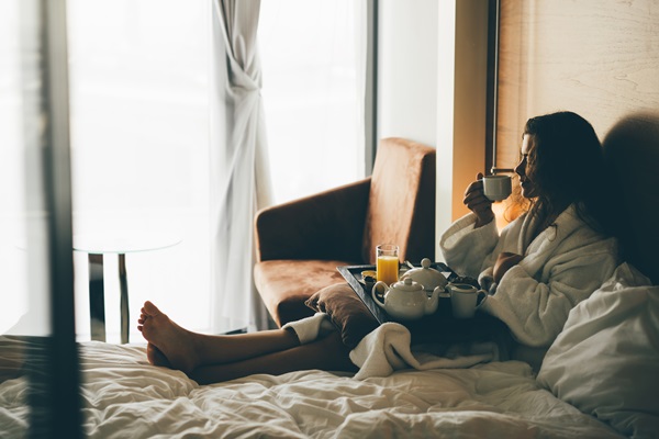 Vrouw drinkt een koffietje in haar hotelbed in de winter in Limburg