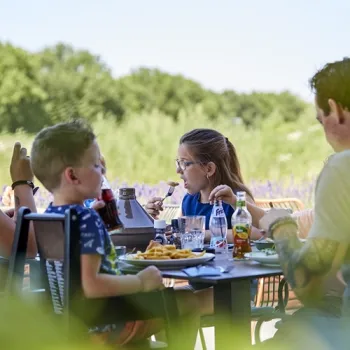 Een gezin zit op het terras van La Selva met uitzicht op het groen.